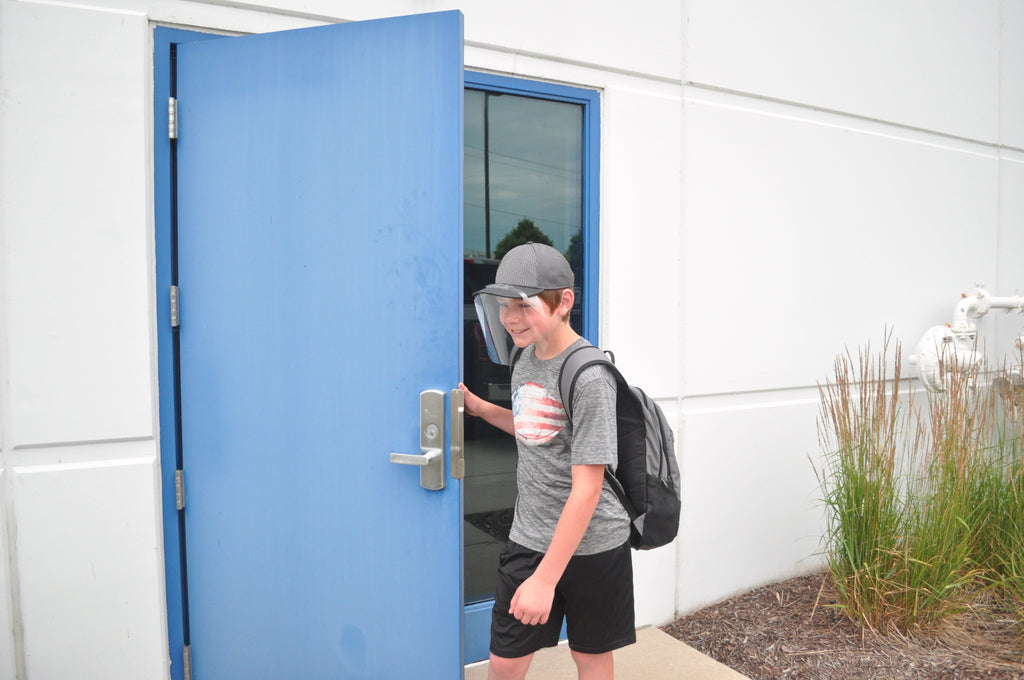 A boy holding the door open while wearing a QuickShield