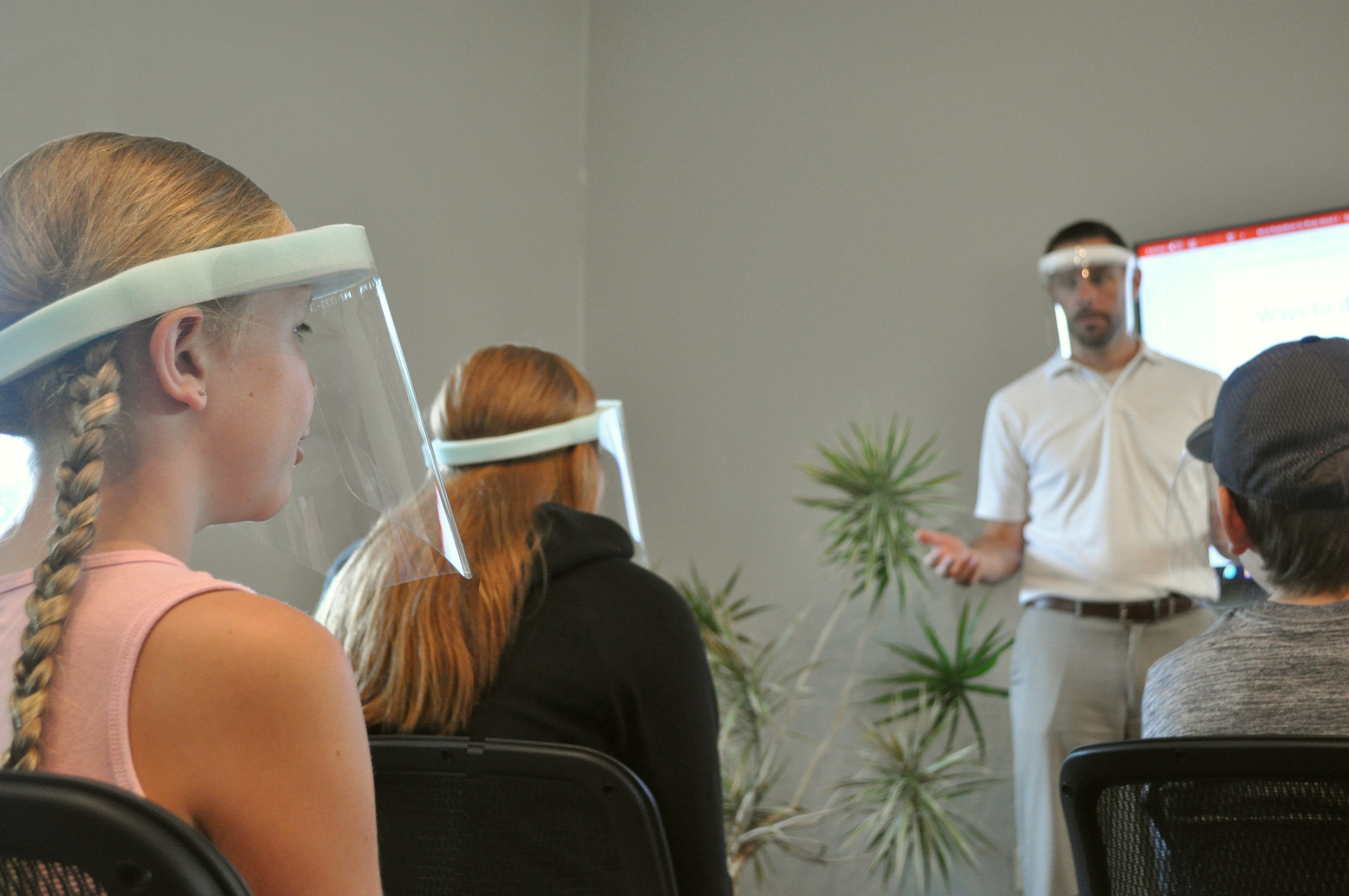 Man wearing a ComfaShield while presenting to a class of students wearing ComfaShields